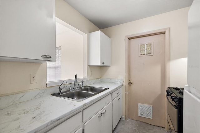 kitchen with range with gas cooktop, sink, light tile patterned flooring, and white cabinets