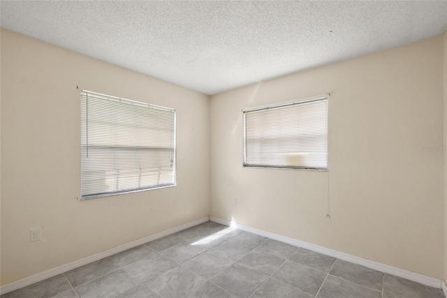 empty room with light tile patterned flooring and a textured ceiling