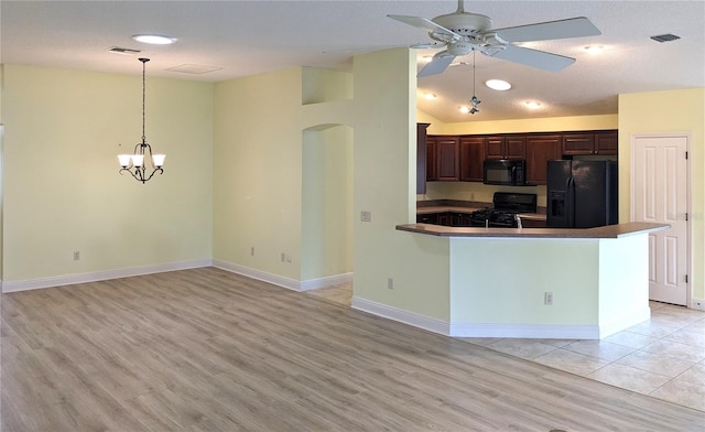 kitchen featuring ceiling fan with notable chandelier, dark brown cabinetry, black appliances, hanging light fixtures, and kitchen peninsula