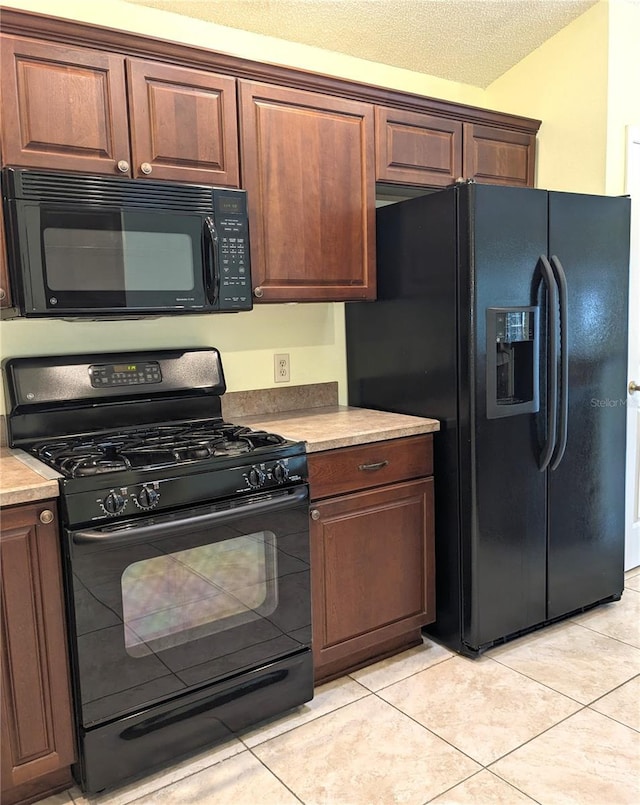 kitchen featuring a textured ceiling, black appliances, and light tile patterned flooring