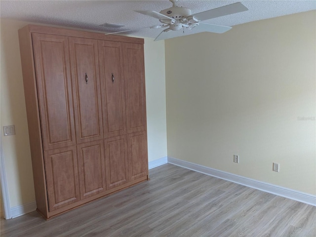 unfurnished bedroom featuring ceiling fan, a textured ceiling, and light hardwood / wood-style flooring