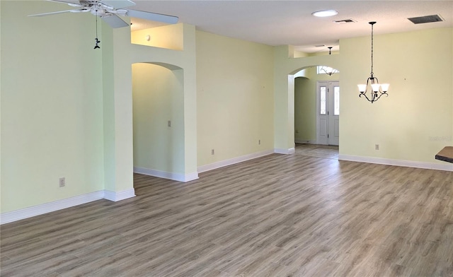 empty room featuring hardwood / wood-style flooring and ceiling fan with notable chandelier