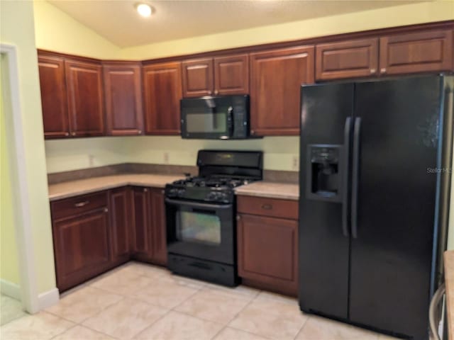 kitchen with black appliances, light tile patterned floors, and lofted ceiling