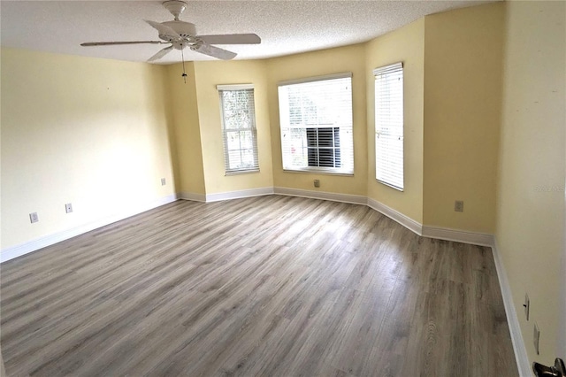 spare room featuring hardwood / wood-style floors, a healthy amount of sunlight, a textured ceiling, and ceiling fan