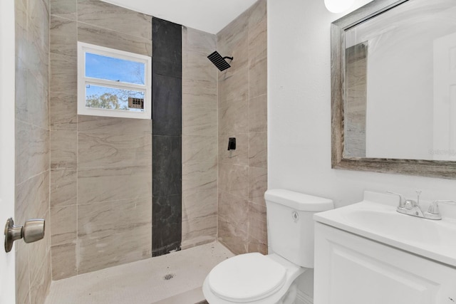 bathroom with a tile shower, vanity, and toilet