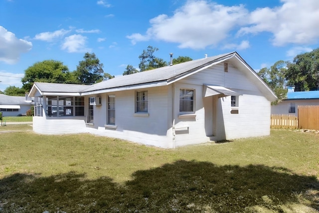 back of property with a yard, a sunroom, and a wall unit AC