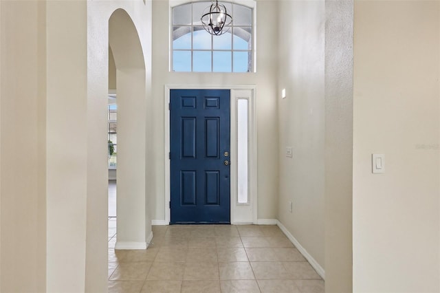 tiled entryway featuring a high ceiling and a notable chandelier