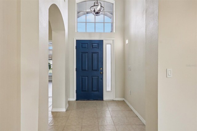 235 Royal Palm Dr, Davenport, FL 33837 - foyer entrance with light tile patterned floors, a chandelier, arched walkways, baseboards, and a towering ceiling