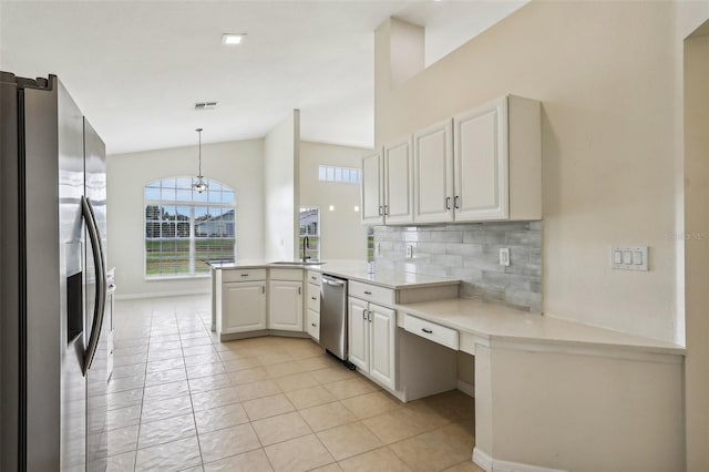 kitchen with tasteful backsplash, stainless steel appliances, white cabinetry, pendant lighting, and kitchen peninsula