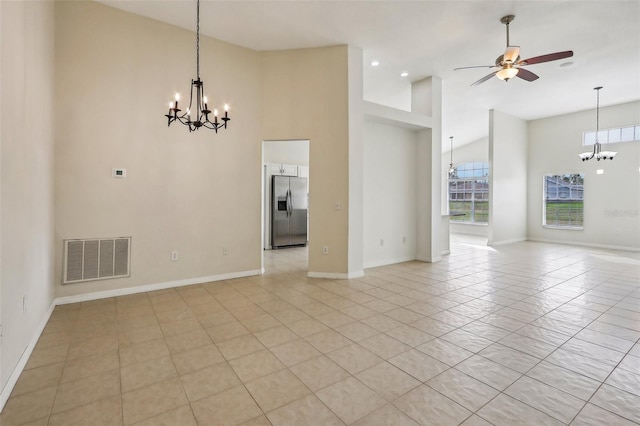 interior space with ceiling fan with notable chandelier, light tile patterned flooring, and a high ceiling