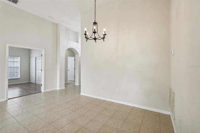 unfurnished room with a high ceiling, a notable chandelier, and light tile patterned floors