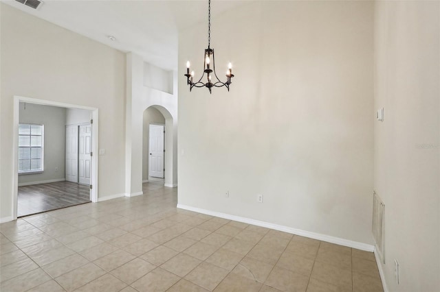 235 Royal Palm Dr, Davenport, FL 33837 - unfurnished room with arched walkways, a chandelier, a high ceiling, light tile patterned floors, and baseboards