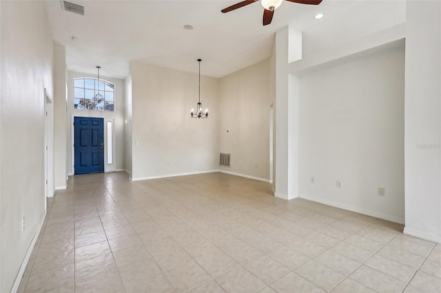 tiled spare room featuring ceiling fan with notable chandelier and a towering ceiling