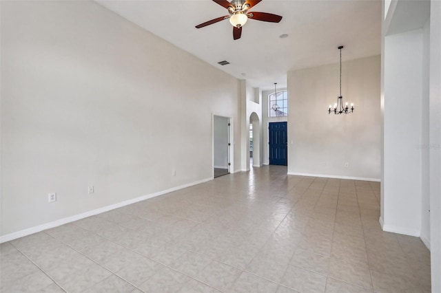 unfurnished room featuring a towering ceiling, ceiling fan with notable chandelier, and light tile patterned floors