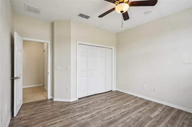 unfurnished bedroom with hardwood / wood-style floors, ceiling fan, and a closet