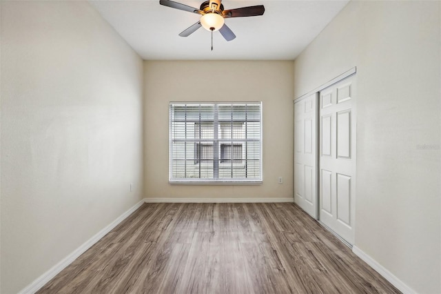 unfurnished bedroom featuring hardwood / wood-style floors, ceiling fan, and a closet