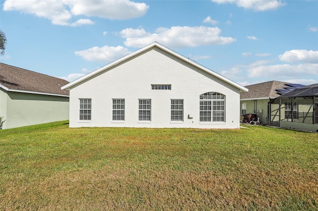 rear view of property featuring a lawn and a lanai