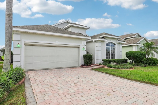 235 Royal Palm Dr, Davenport, FL 33837 - view of front of house with stucco siding, decorative driveway, a garage, and roof with shingles