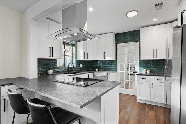 kitchen featuring white cabinetry, sink, a kitchen breakfast bar, island exhaust hood, and kitchen peninsula