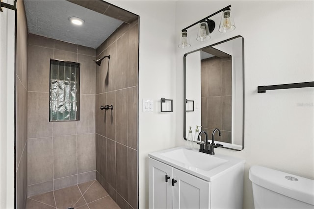 bathroom featuring tiled shower, vanity, and toilet