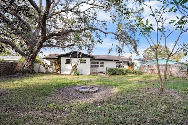 rear view of property with a fire pit and a lawn