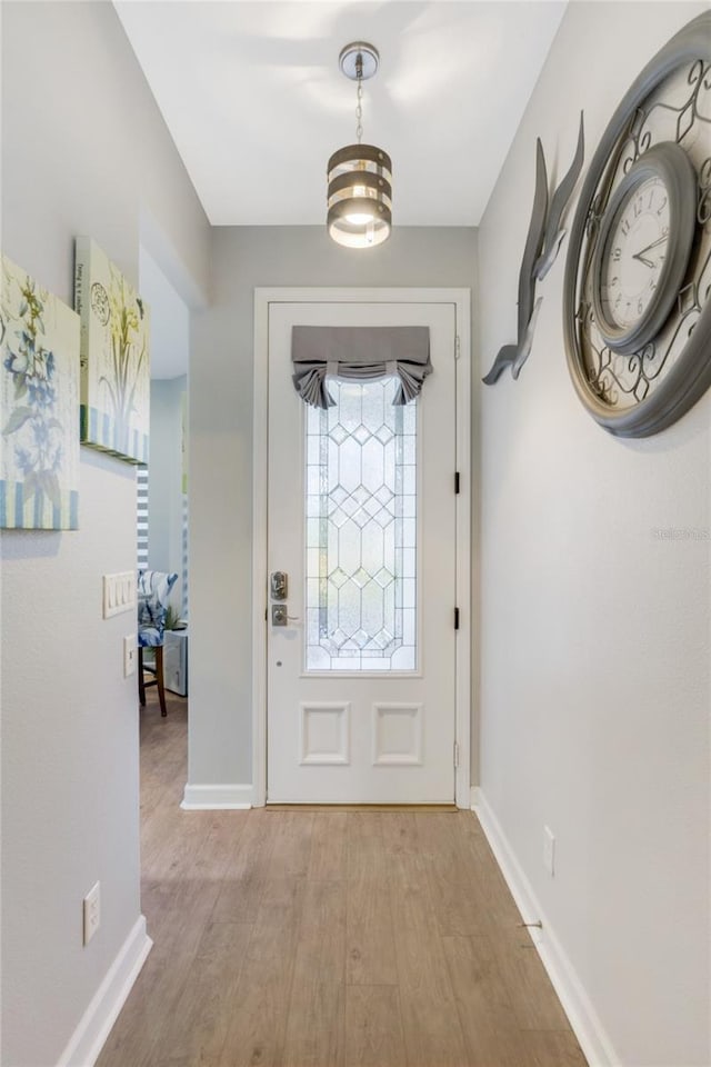 foyer entrance with light hardwood / wood-style floors and a notable chandelier