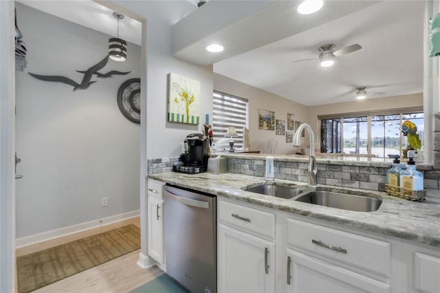 kitchen with white cabinets, sink, light hardwood / wood-style flooring, stainless steel dishwasher, and light stone countertops