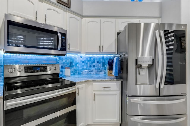 kitchen with light stone countertops, decorative backsplash, white cabinetry, and stainless steel appliances