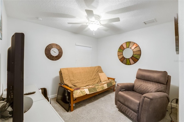 living area featuring ceiling fan, a textured ceiling, and light carpet