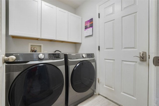 laundry room with washer and clothes dryer, light hardwood / wood-style floors, and cabinets