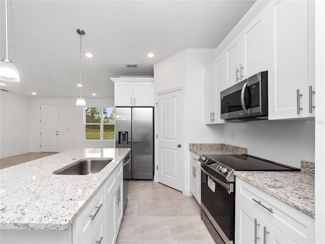 kitchen with an island with sink, light stone countertops, pendant lighting, appliances with stainless steel finishes, and white cabinetry