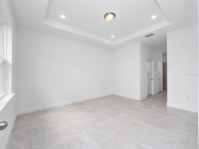 tiled empty room with a raised ceiling