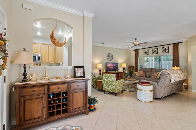 tiled living room with ceiling fan and crown molding