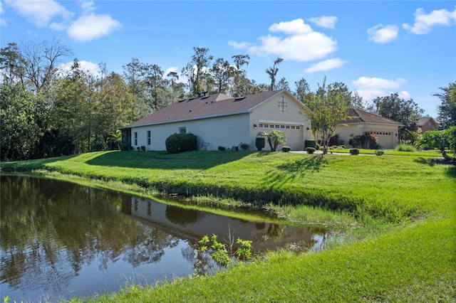 exterior space with a garage, a water view, and a yard