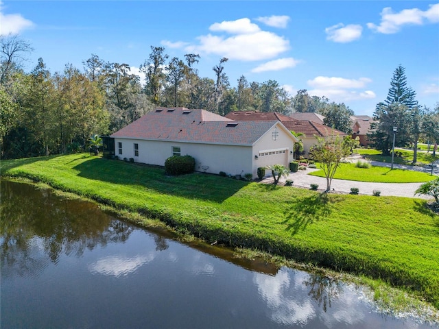 view of property exterior with a yard, a garage, and a water view