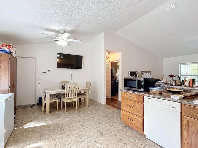 kitchen with ceiling fan, lofted ceiling, a textured ceiling, and white dishwasher