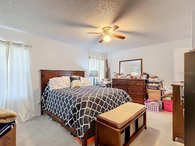 bedroom featuring a textured ceiling, light colored carpet, and ceiling fan