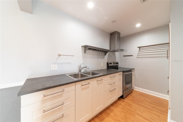 kitchen featuring stainless steel electric range oven, sink, wall chimney exhaust hood, and light wood-type flooring