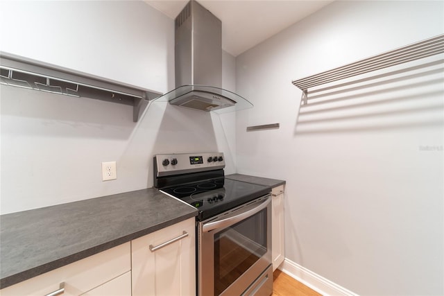 kitchen with light hardwood / wood-style flooring, wall chimney range hood, and electric stove