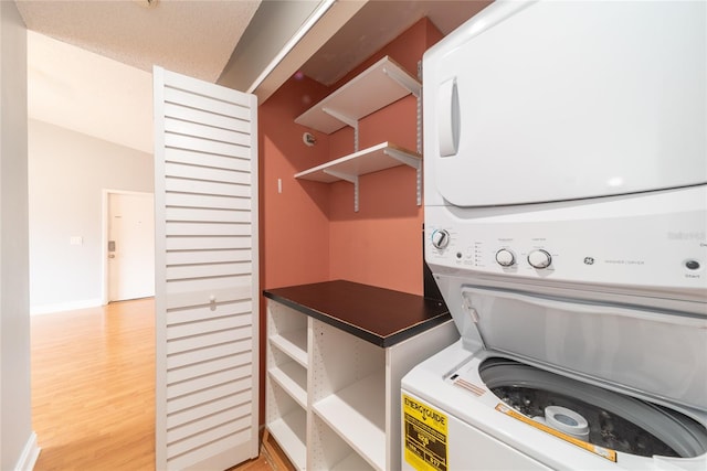 laundry room featuring light hardwood / wood-style floors and stacked washer / dryer