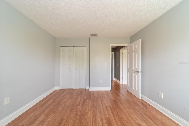 unfurnished bedroom with a closet, a textured ceiling, and light hardwood / wood-style floors