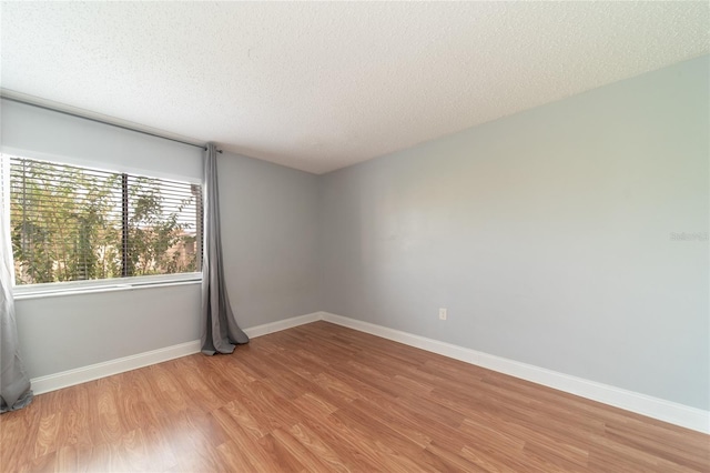 unfurnished room featuring light wood-type flooring and a textured ceiling