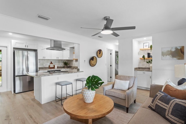 living room with ceiling fan and light hardwood / wood-style flooring