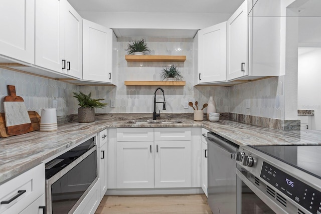 kitchen with white cabinetry, sink, light stone countertops, and stainless steel appliances