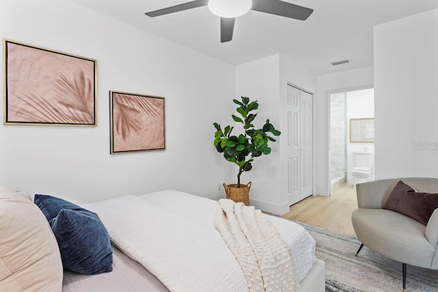 bedroom with ceiling fan, ensuite bath, and light wood-type flooring