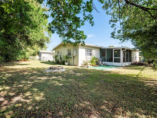 rear view of house with a lawn, central AC, and a sunroom