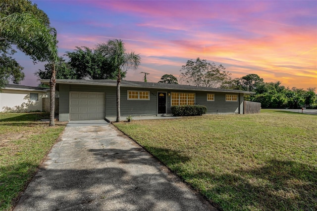 ranch-style house featuring a garage and a lawn