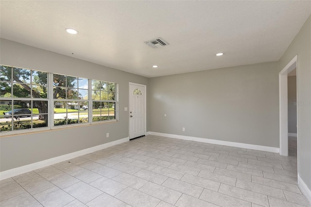 tiled spare room featuring a textured ceiling