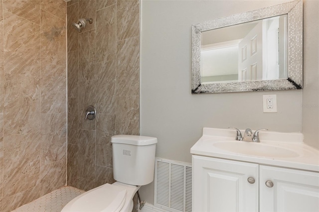 bathroom featuring toilet, vanity, and tiled shower