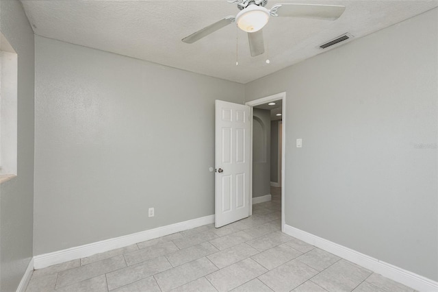 tiled spare room with a textured ceiling and ceiling fan